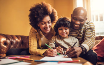 Young African American family having fun while drawing together at home.